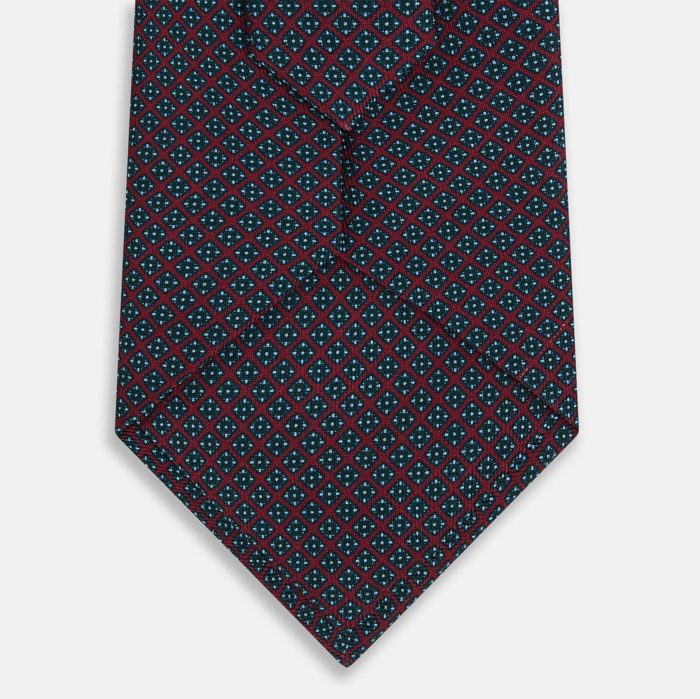The Turnbull & Asser Magenta and Navy Square-Patterned Silk Tie is neatly rolled on a plain light background.
