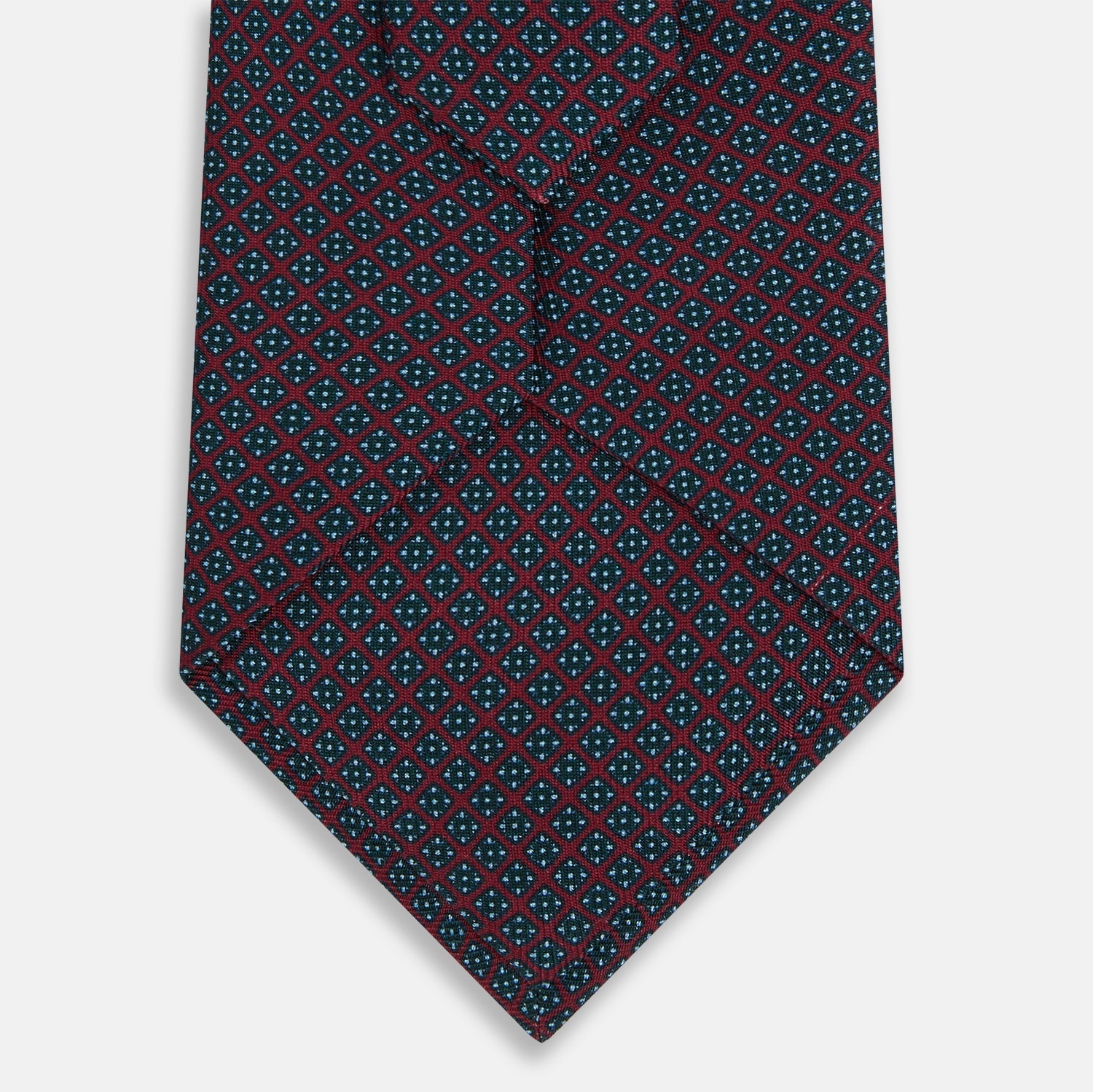 View 3 of product The Turnbull & Asser Magenta and Navy Square-Patterned Silk Tie is neatly rolled on a plain light background.