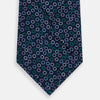View 3 of product The Turnbull & Asser Green and Lilac Dark Navy Printed Silk Tie features a pattern of multicolored rings—an elegant formal accessory, shown rolled on a white background.