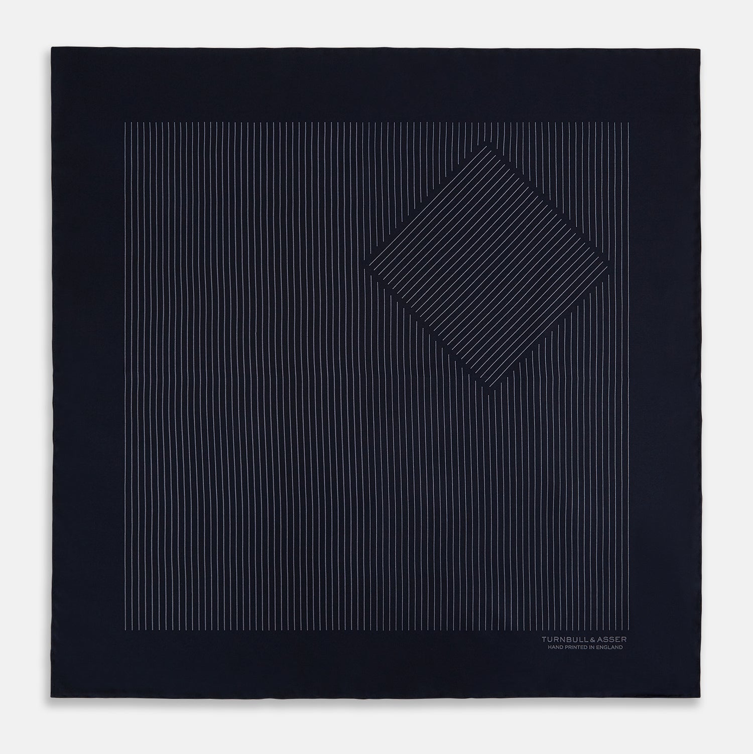 View 3 of product The Navy and Charcoal Stripe Silk Pocket Square by Turnbull & Asser features fine hand-rolled edges, thin white stripes on navy, and TURNBULL & ASSER HAND PRINTED IN ENGLAND in white on the corner.