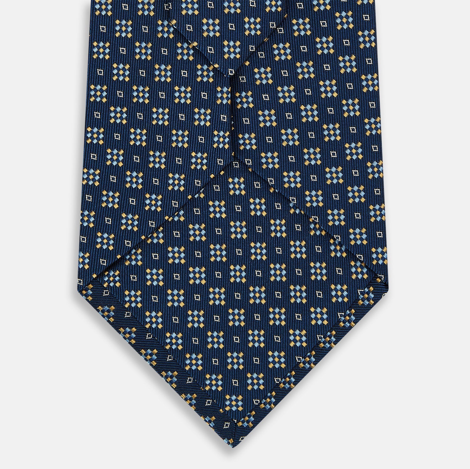 View 3 of product The Turnbull & Asser Navy Diamond Silk Tie features a diamond pattern of small white and yellow squares, embodying British craftsmanship, shown on a plain white background.