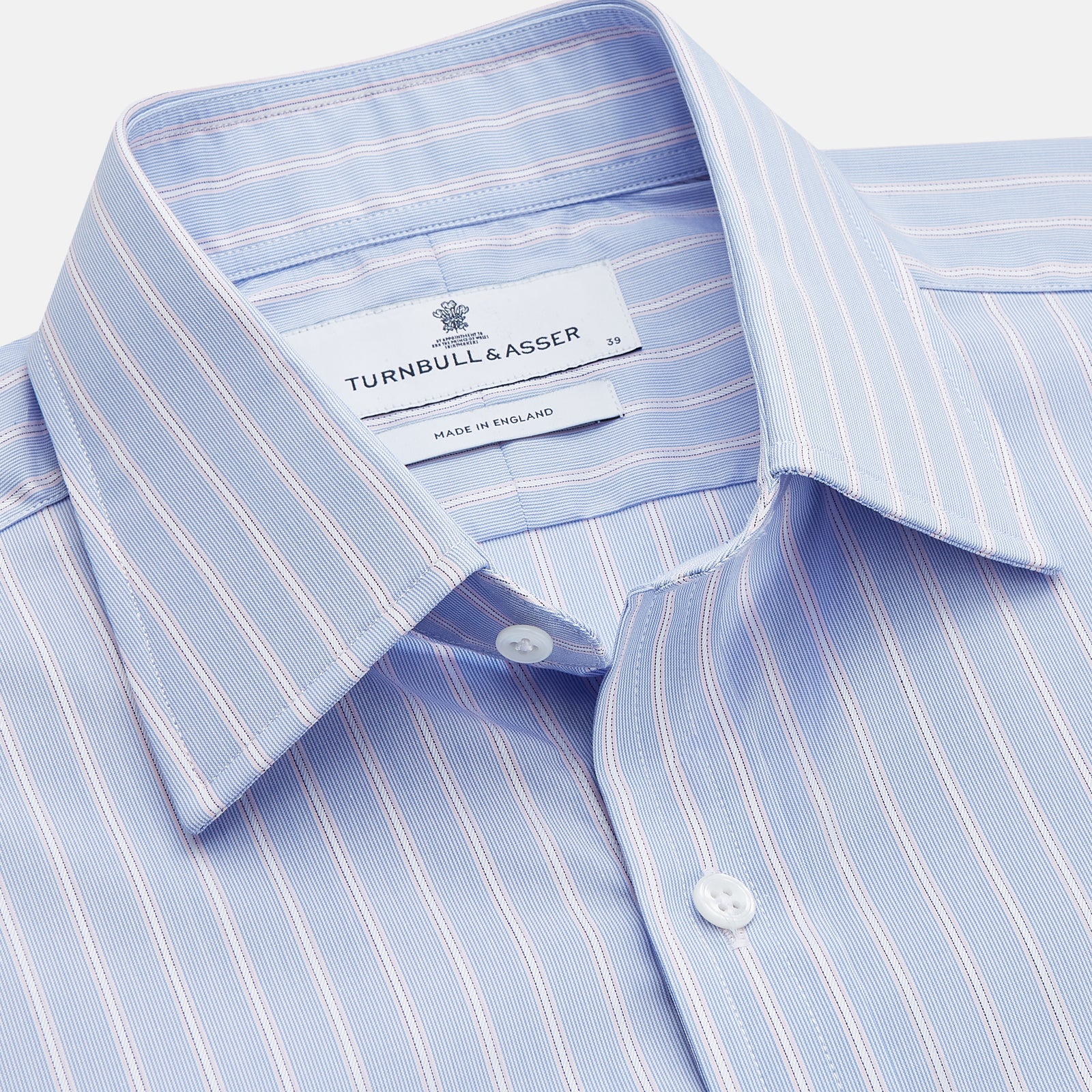View 2 of product The Turnbull & Asser Blue Multi Stripe Cotton Regular Fit Whitby Shirt features white vertical stripes, long sleeves, button-down front, pointed collar, and buttoned cuffs, shown laid flat on a white background.