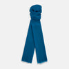View 1 of product The Turnbull & Asser Steel Blue Cashmere Scarf, featuring a soft texture and slightly frayed edges, is neatly folded and tied in a loose knot against a white background.