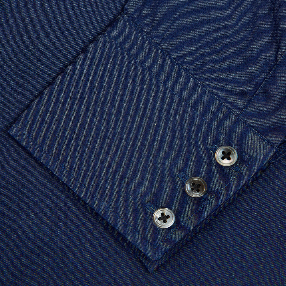 The Turnbull & Asser Dark Blue Denim-Cashmere Shirt features a Regent collar, long sleeves, and 3-button cuffs, neatly folded and displayed on a plain light background.