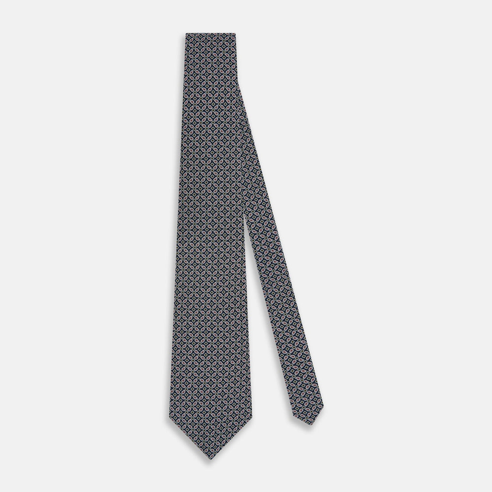 The Turnbull & Asser Navy Mélange Paisley and Square Print Silk Tie is crafted from fine silk, showcasing a repeating paisley and square pattern in blue tones, elegantly rolled for display on a white background.