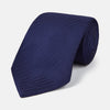 View 1 of product The PLAIN HERRINGBONE NAVY TIE by Turnbull & Asser, crafted from silk with a subtle pattern, is elegantly rolled and displayed against a plain white background.