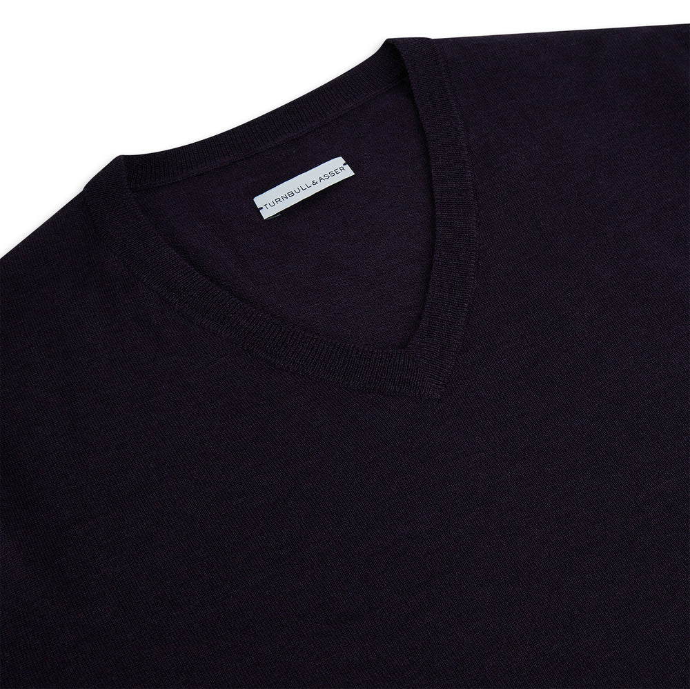 The Turnbull & Asser Dark Purple Fine Merino V-Neck Jumper features long sleeves and a classic knit, shown against a white background.