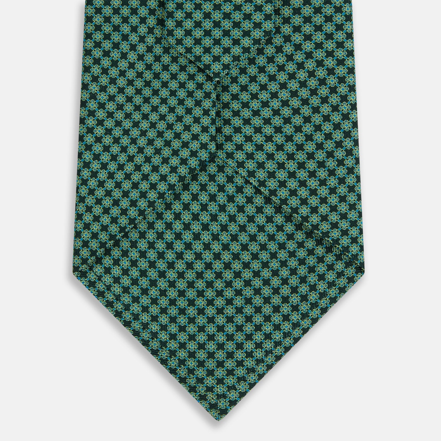 View 3 of product The Forest Green Geometric Floral Printed Silk Tie by Turnbull & Asser is shown rolled up on a white background, its English silk material featuring an elegant green and turquoise pattern.
