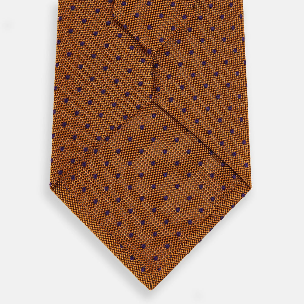 The Turnbull & Asser Purple and Orange Micro Dot Silk Tie, featuring a vibrant polka dot pattern, makes a bold men's accessory and is shown rolled up on a white background.