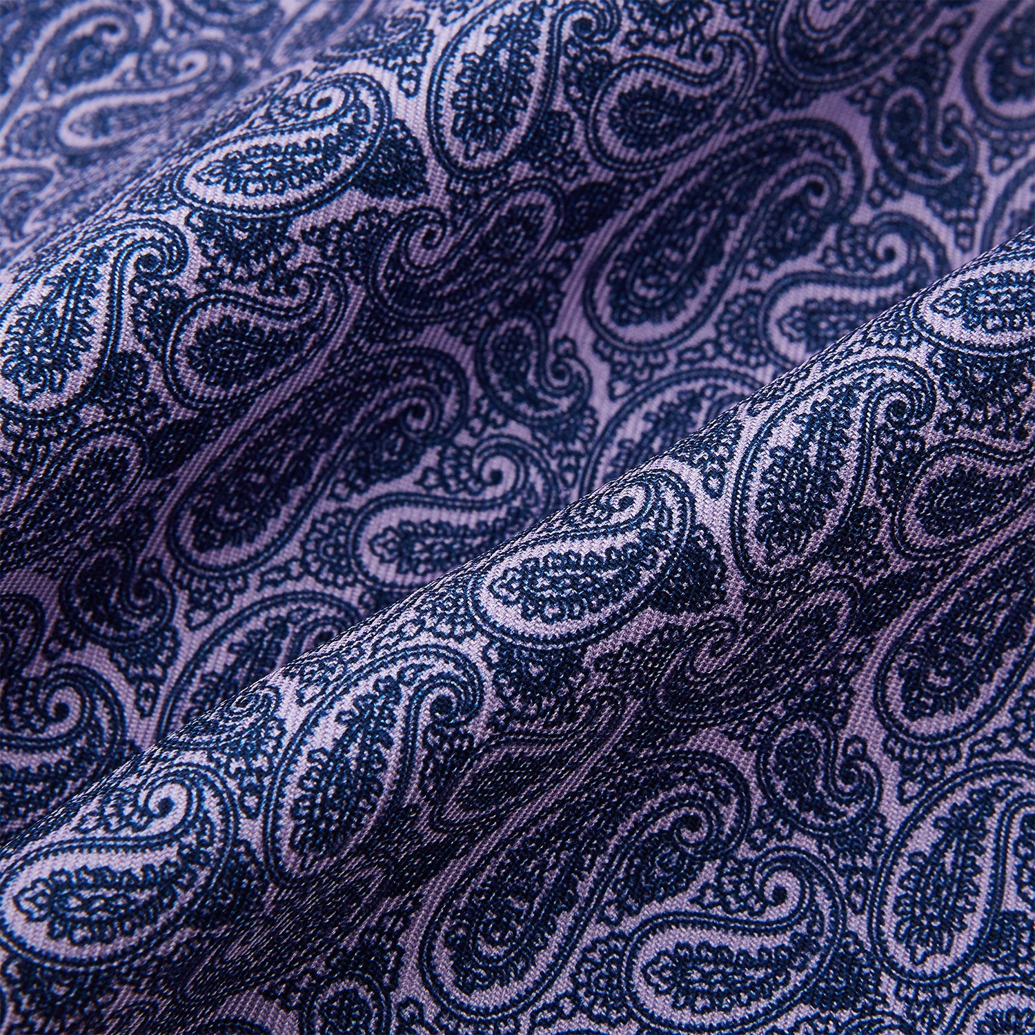 View 4 of product The Turnbull & Asser Lilac Paisley Silk Cravat showcases British elegance with its dark blue paisley pattern on a lilac background, beautifully displayed on a white surface.