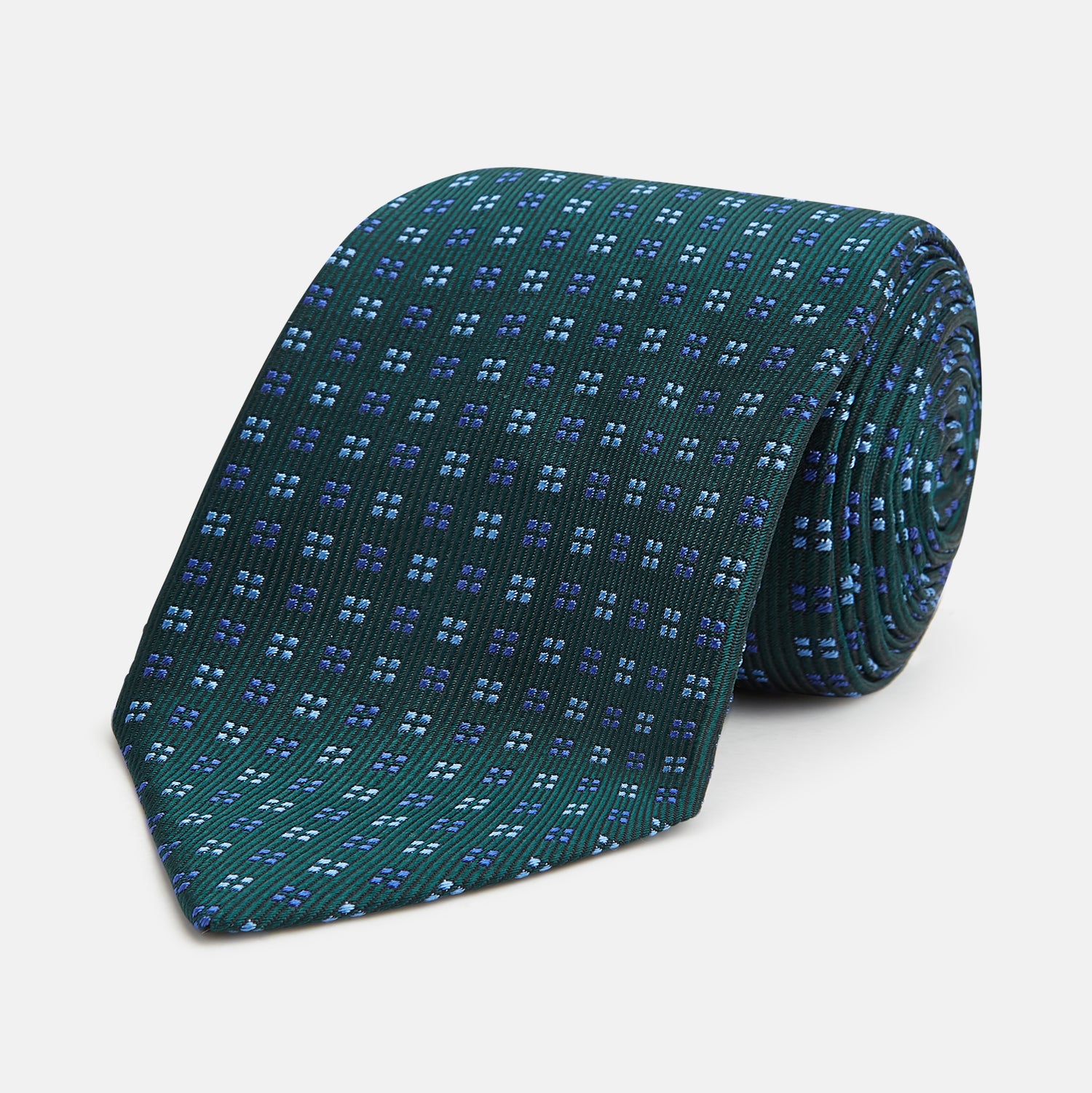 View 1 of product The MINI SQUARE SPOT FOREST GREEN BLUE TIE by Turnbull & Asser is a classic men's accessory, featuring a rolled-up green silk design with small blue geometric patterns—perfect for the modern gentleman.