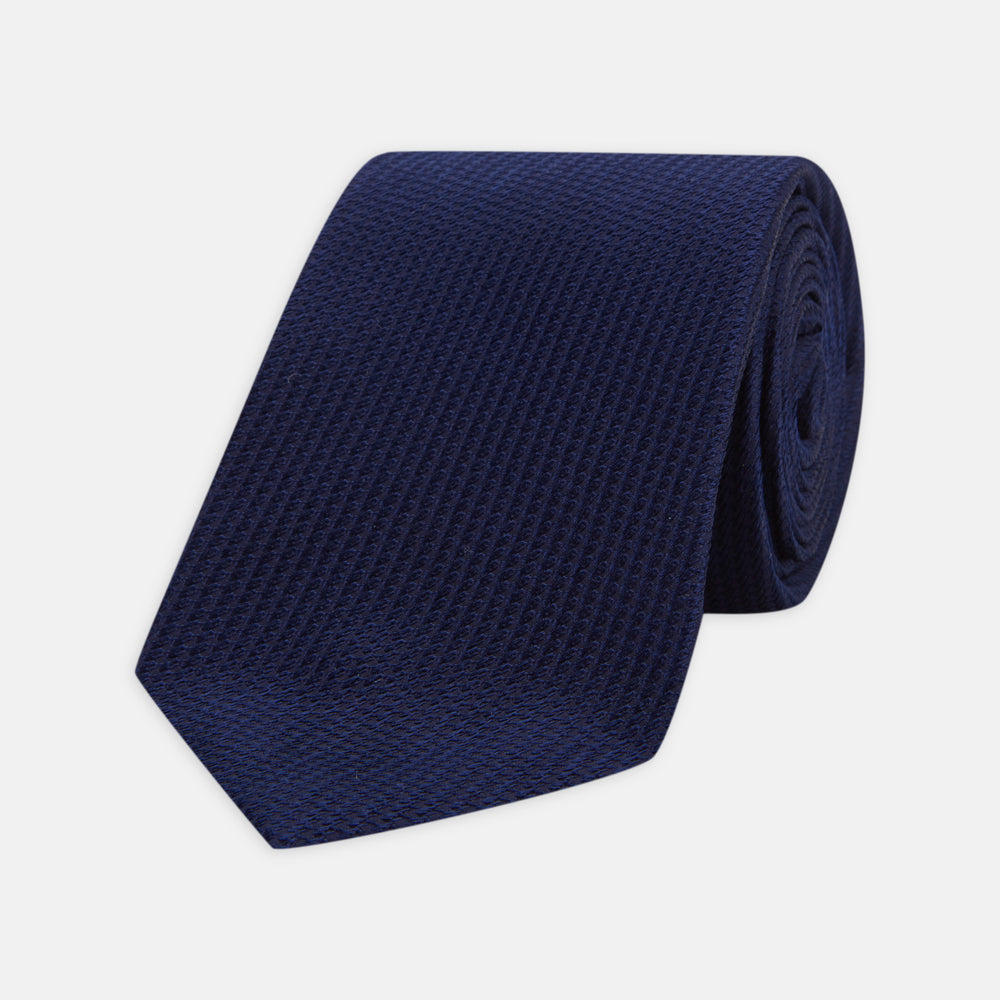 The Turnbull & Asser Seven-Fold Navy Lace Silk Tie is shown on a white background, rolled at one end with the pointed tip facing forward.