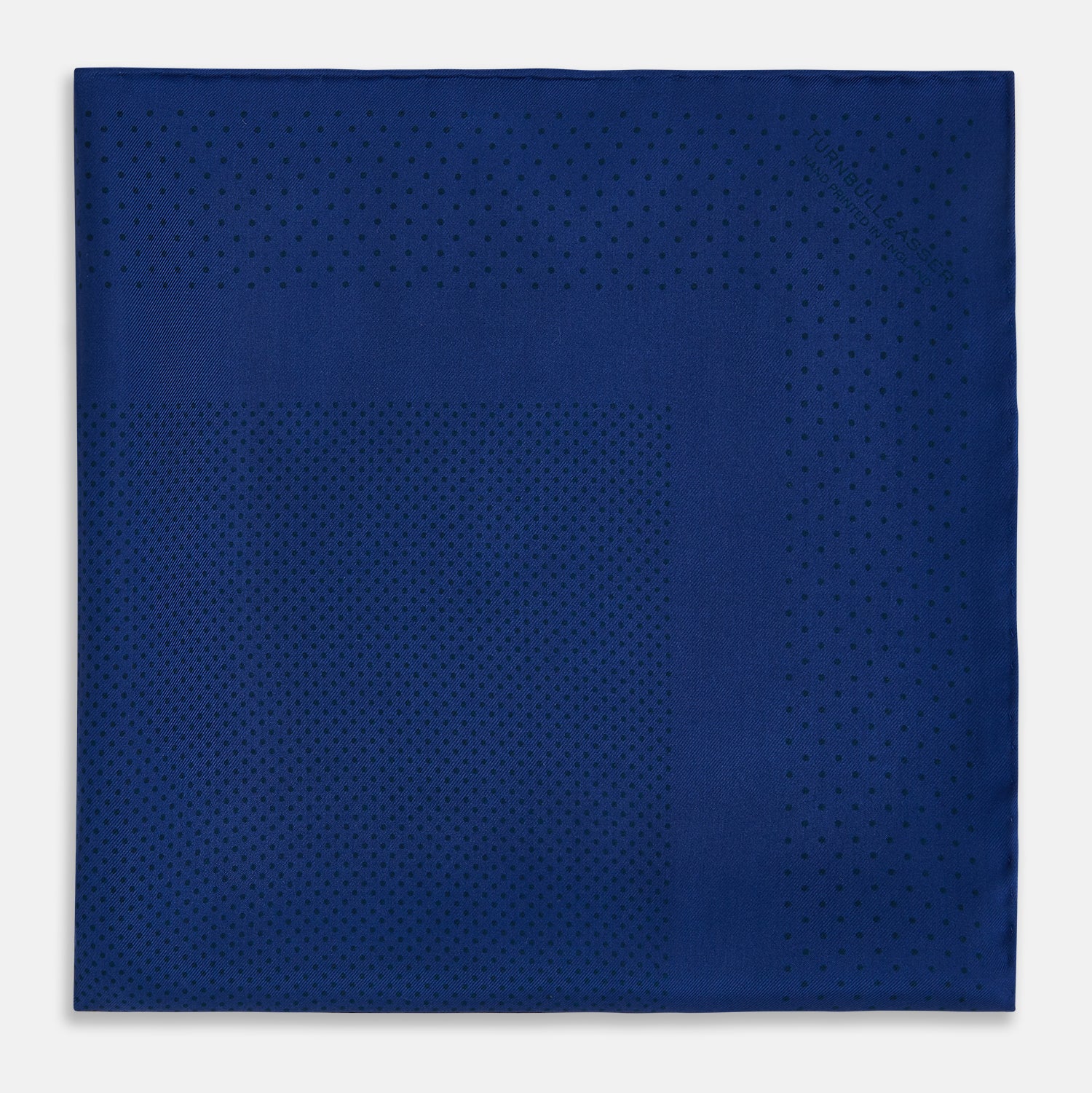 View 3 of product The Turnbull & Asser Navy Dot Silk Pocket Square, folded with neat hand-rolled edges, features a subtle navy polka dot pattern on dark blue silk and is shown against a white background.