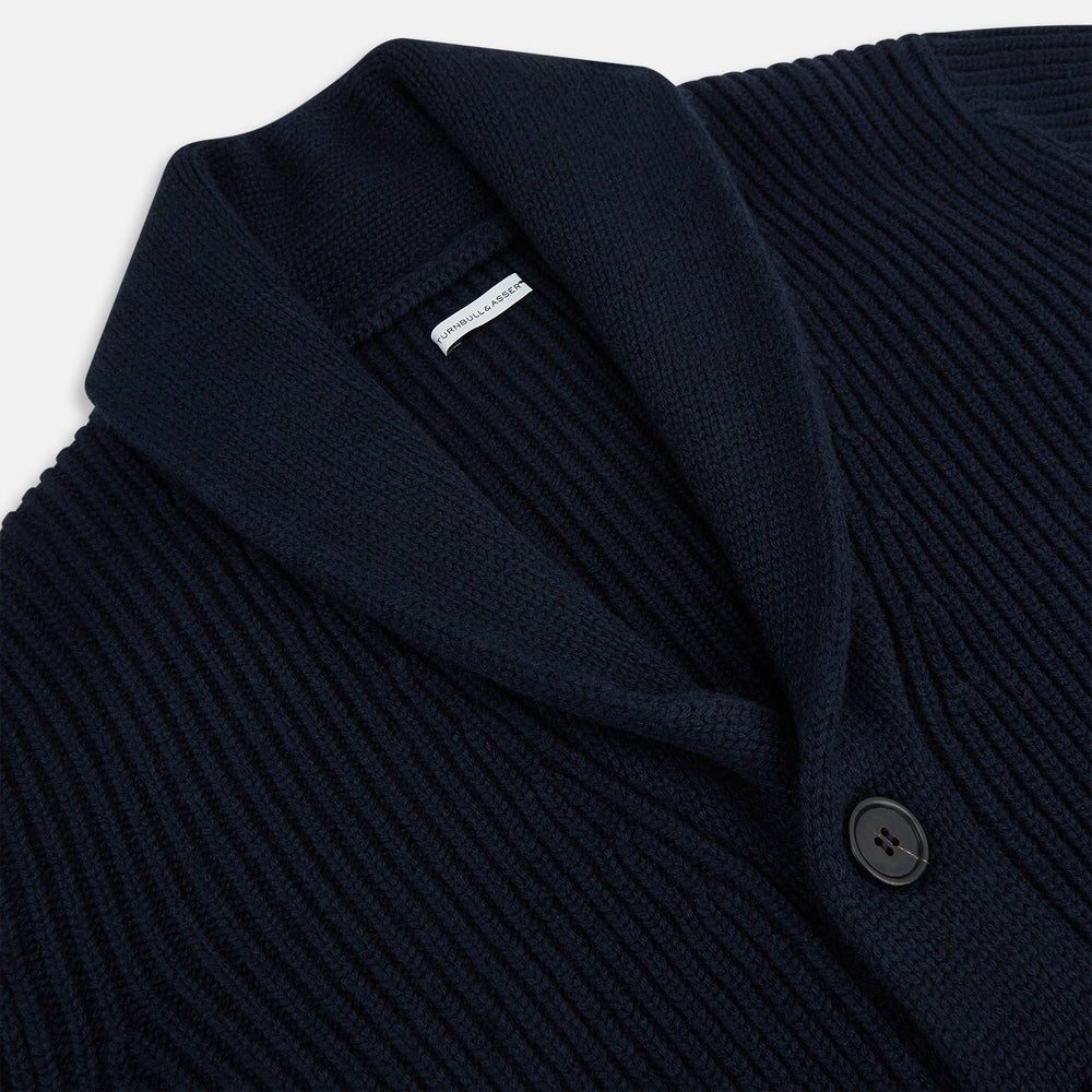 The Turnbull & Asser Midnight Blue Cashmere Shawl Collar Cardigan features ribbed fabric, five black front buttons, a shawl collar, and two front patch pockets, shown against a plain light background.