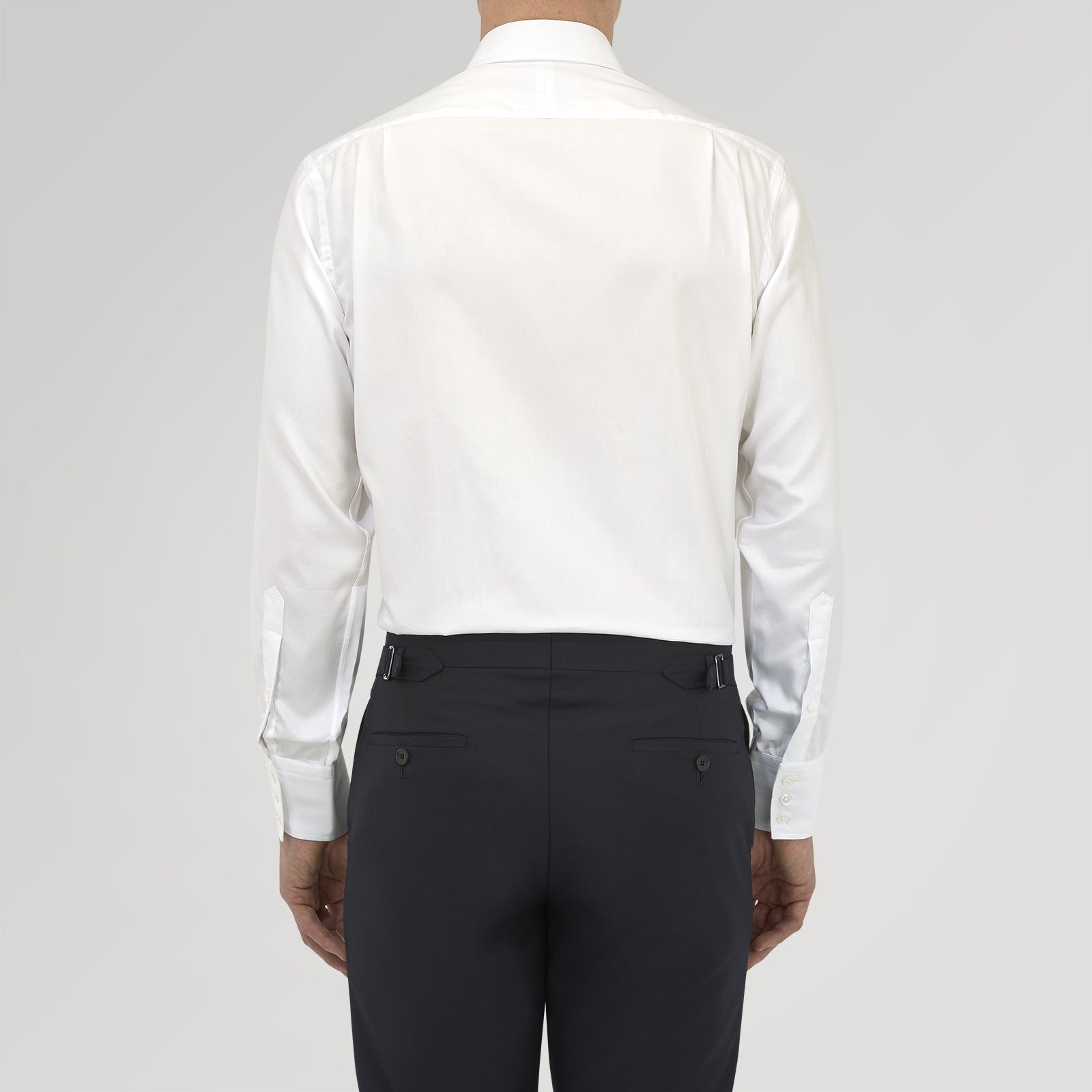 View 3 of product A neatly folded White Sea Island Quality Cotton Twill Shirt by Turnbull & Asser, featuring a T&A collar and 3-button cuffs, is displayed on a light grey background with a label visible inside the collar.