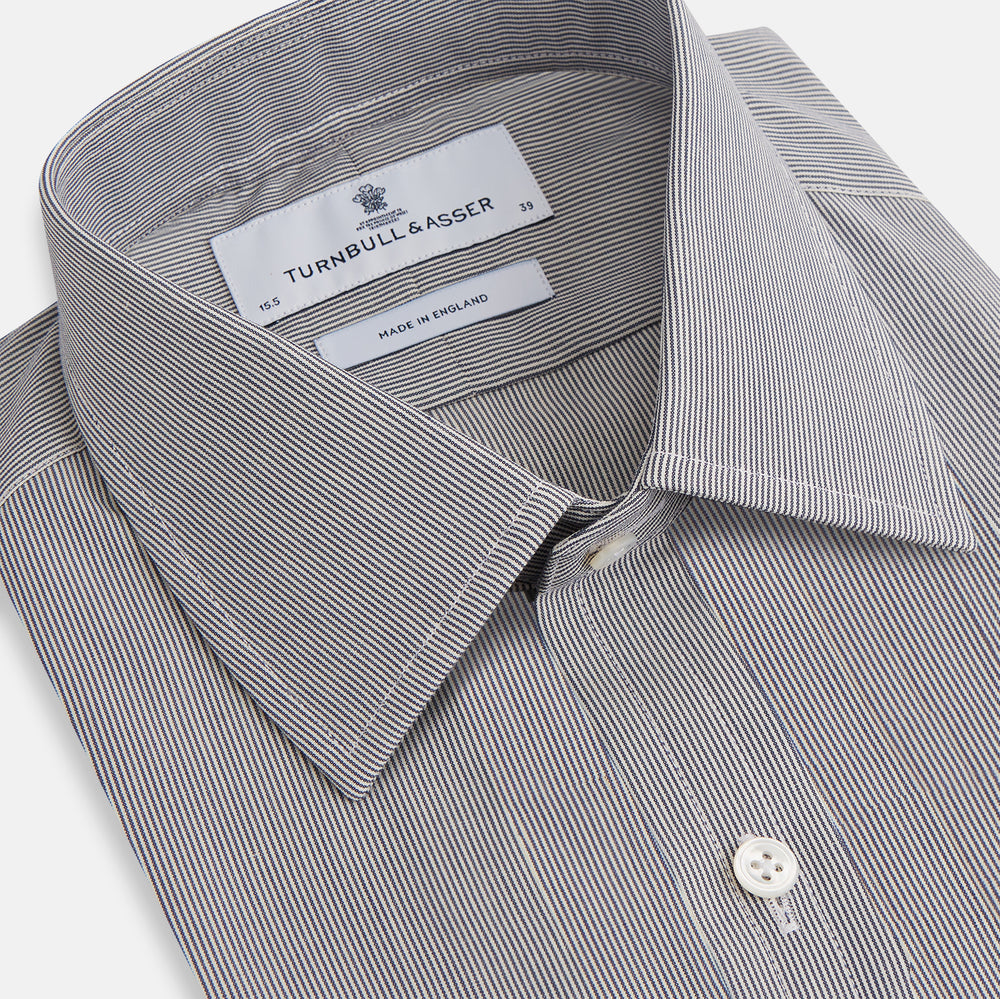 The Turnbull & Asser Navy Fine Stripe Mayfair Shirt, a long-sleeve, button-up with a classic collar, features fine navy stripes and white buttons, shown laid flat on a white background.