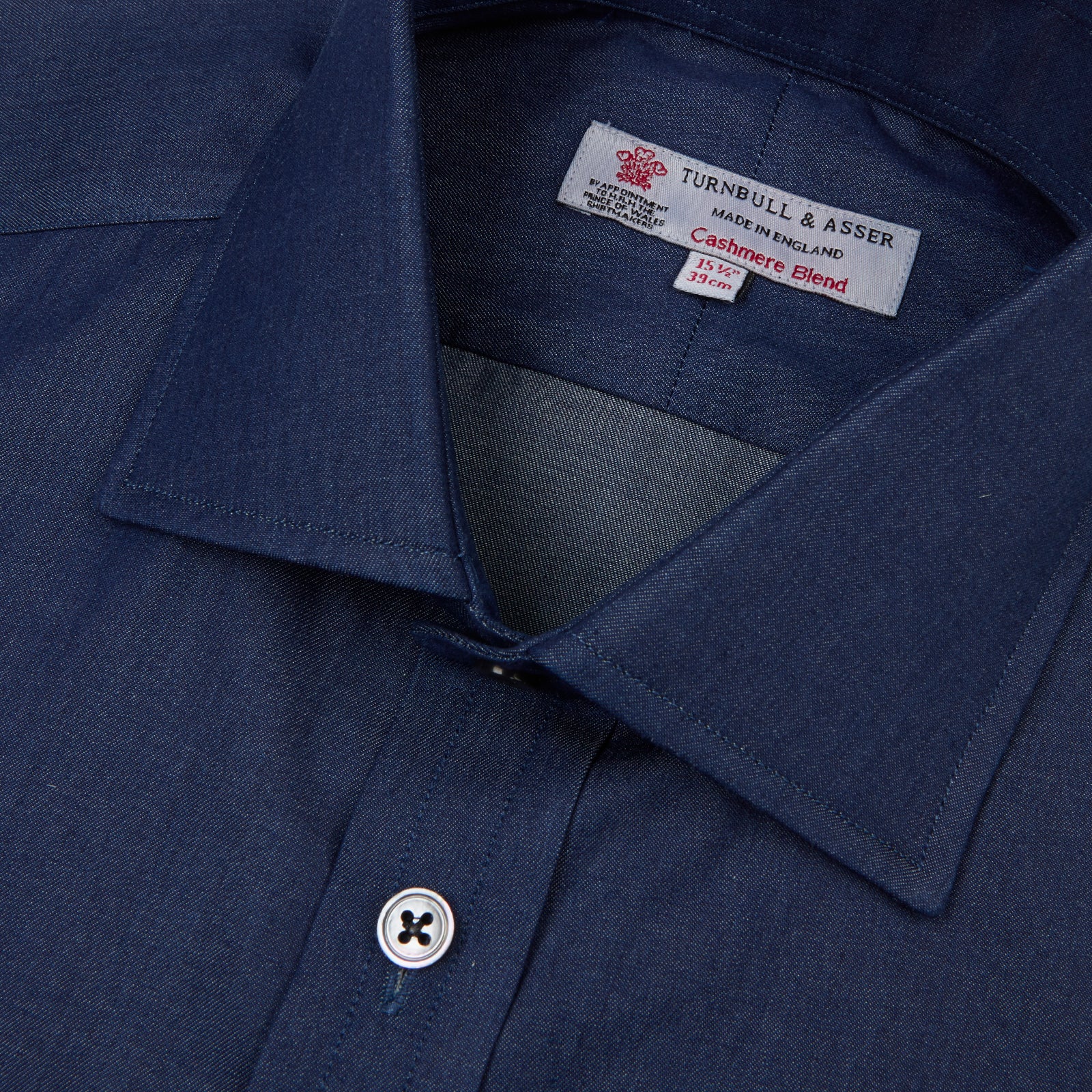 View 4 of product The Turnbull & Asser Dark Blue Denim-Cashmere Shirt features a Regent collar, long sleeves, and 3-button cuffs, neatly folded and displayed on a plain light background.