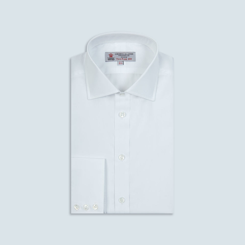 A neatly folded Turnbull & Asser Two-Fold 200 White Cotton Shirt with a Regent collar and 3-button cuffs, crafted from breathable fabric, is displayed on a light grey background with the label visible inside the collar.