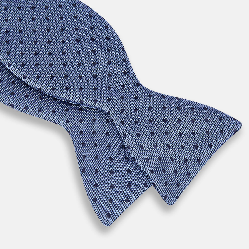 The Turnbull & Asser Blue Micro Dot Silk Bow Tie features a subtle textured pattern with small navy polka dots, shown on a white background—an ideal accessory for smart attire.