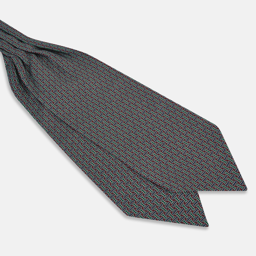 The Forest Green and Red Weave Patterned Silk Cravat by Turnbull & Asser features an elegant geometric design in rich hues, folded to a pointed end for a classic, British-inspired look.
