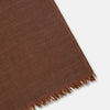 View 2 of product The Turnbull & Asser Brown Cashmere Scarf is ultra-soft with a smooth texture, short frayed edges, and is tied in a simple knot. Displayed against a plain white background.