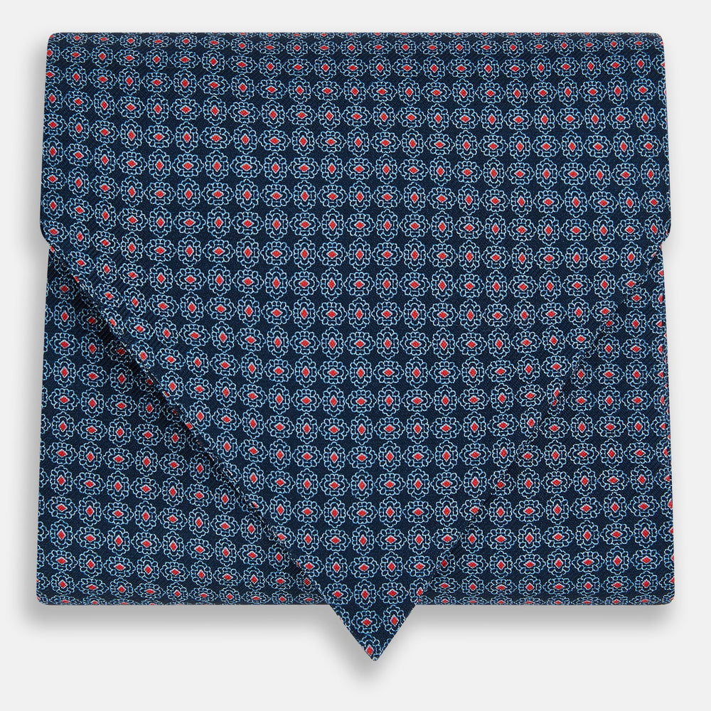 The Turnbull & Asser Navy and Red Rosette Cravat is adorned with a repeating geometric pattern of red, white, and light blue circles—an ideal formal accessory displayed against a white background.