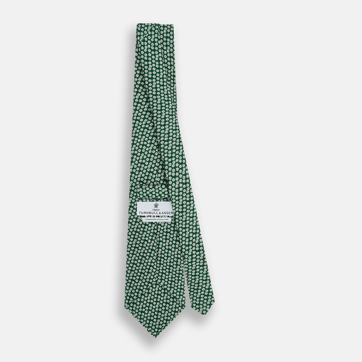 View 4 of product The Turnbull & Asser Forest Green Flower Patterned Silk Tie, crafted from fine English silk, features a repeating white floral design and is shown rolled up on a white background.