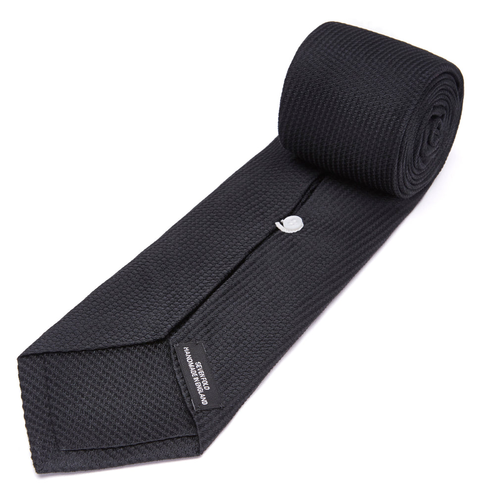 Turnbull & Asser's Seven-Fold Black Lace Silk Tie, featuring a textured finish and pointed tip, is elegantly rolled and displayed on a white background—a timeless accessory for any luxury neckwear collection.
