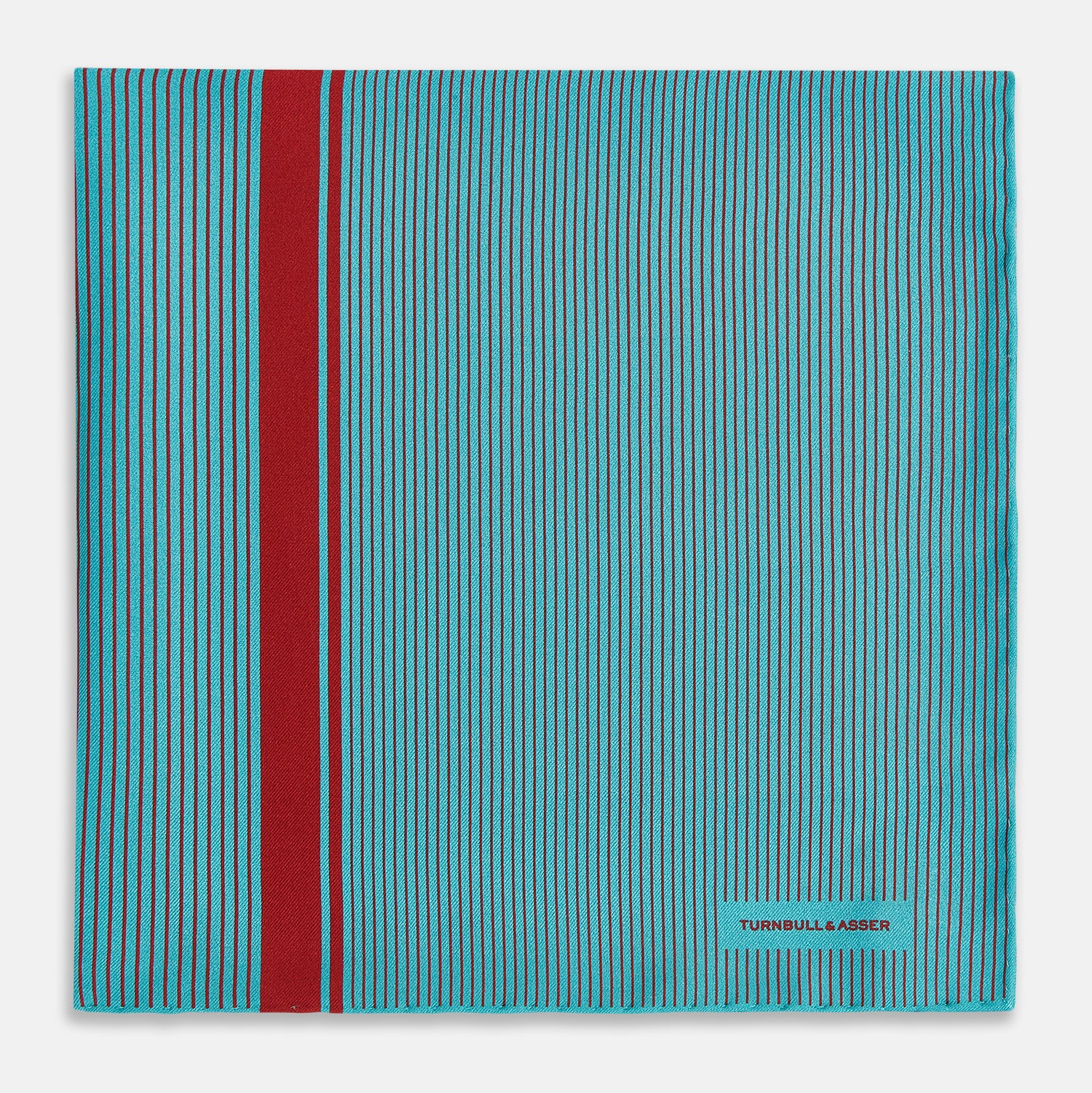 Image 3 of product The Turnbull & Asser Turquoise and Red Stripe Silk Pocket Square features thin navy stripes with a bold vertical red stripe, partially folded to reveal the reverse pattern and the brand's logo, showcasing its British heritage.
