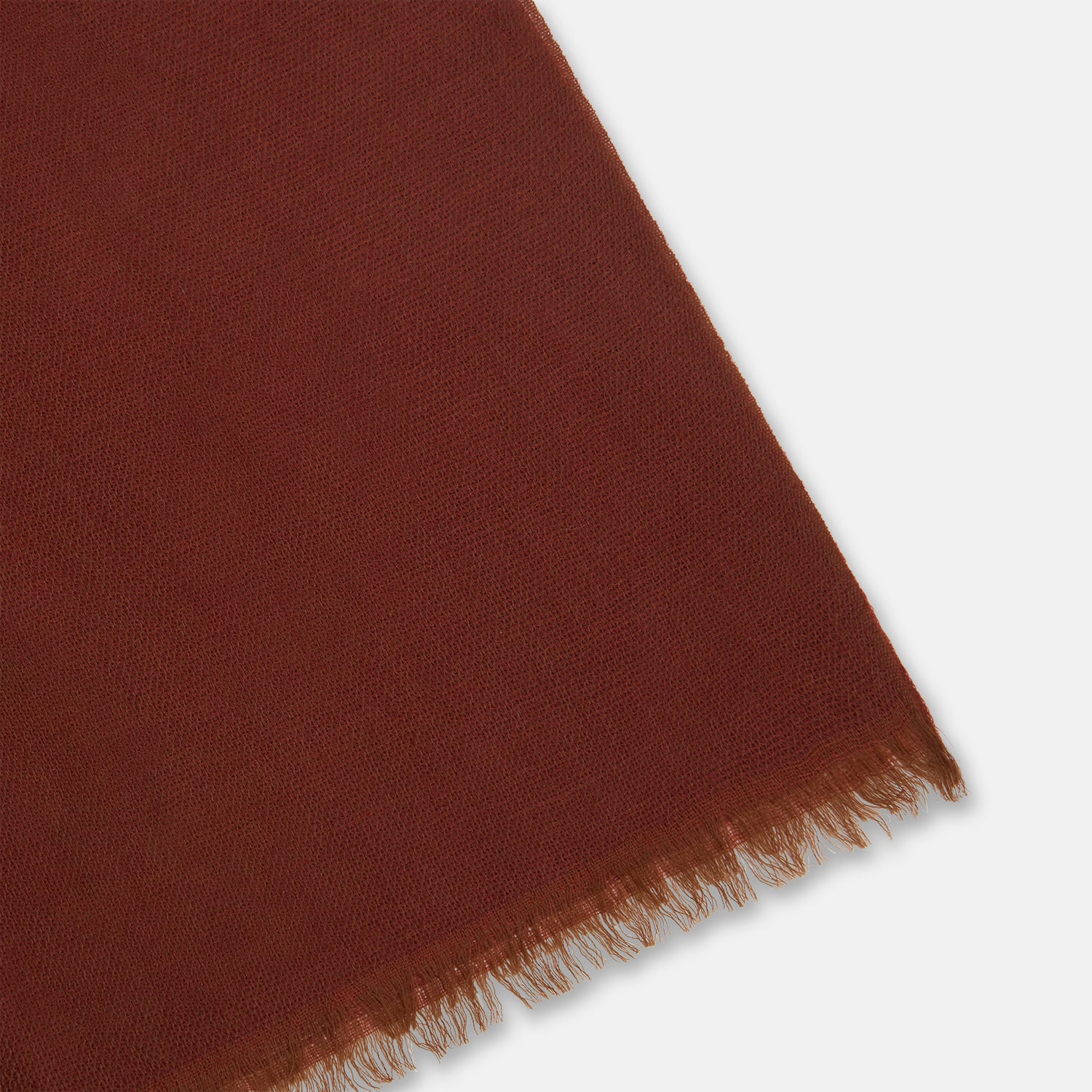 View 2 of product The Plush Burgundy Cashmere Scarf by Turnbull & Asser is neatly folded and draped, featuring subtle frayed edges, and displayed on a plain light background.