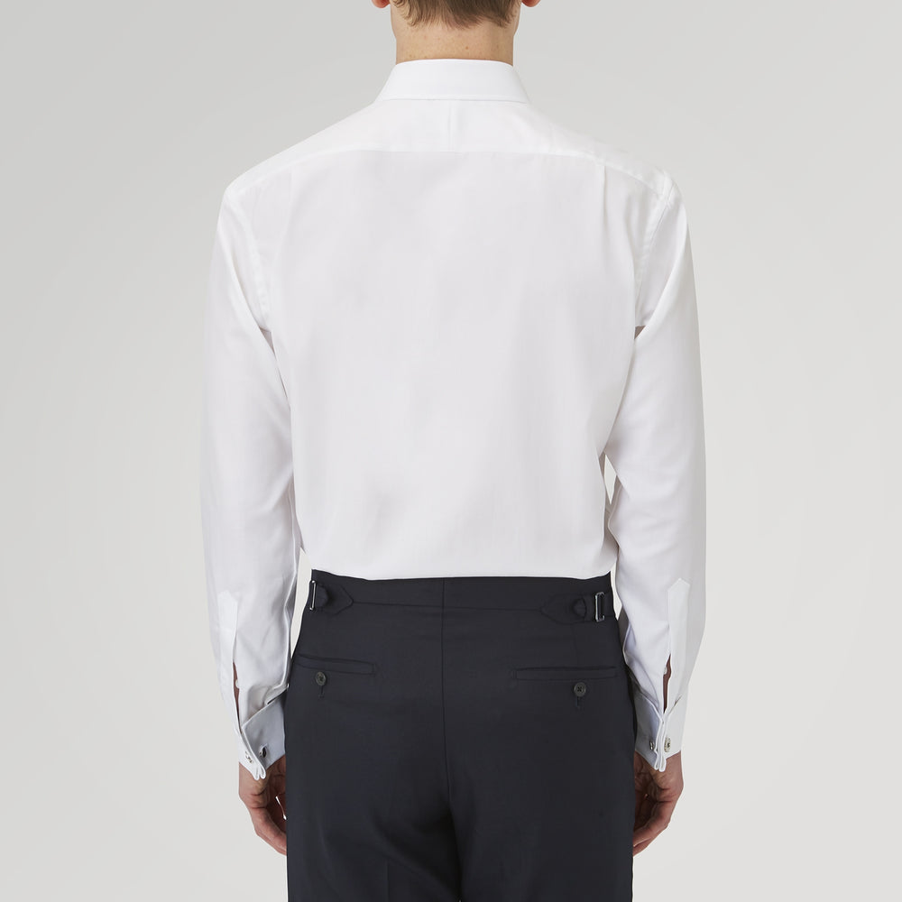 The Turnbull & Asser White Herringbone Sea Island Quality Cotton Shirt features a T&A collar, double cuffs, and chest pocket. Crafted for luxury with a classic design, it’s shown neatly folded against a light grey background—ideal for evening wear.