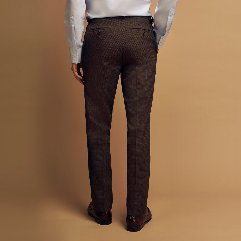 The Brown Puppytooth Wool Jonathan Trousers by Turnbull & Asser are straight-leg tailored trousers with belt loops, side pockets, and a front crease, shown on a white background.