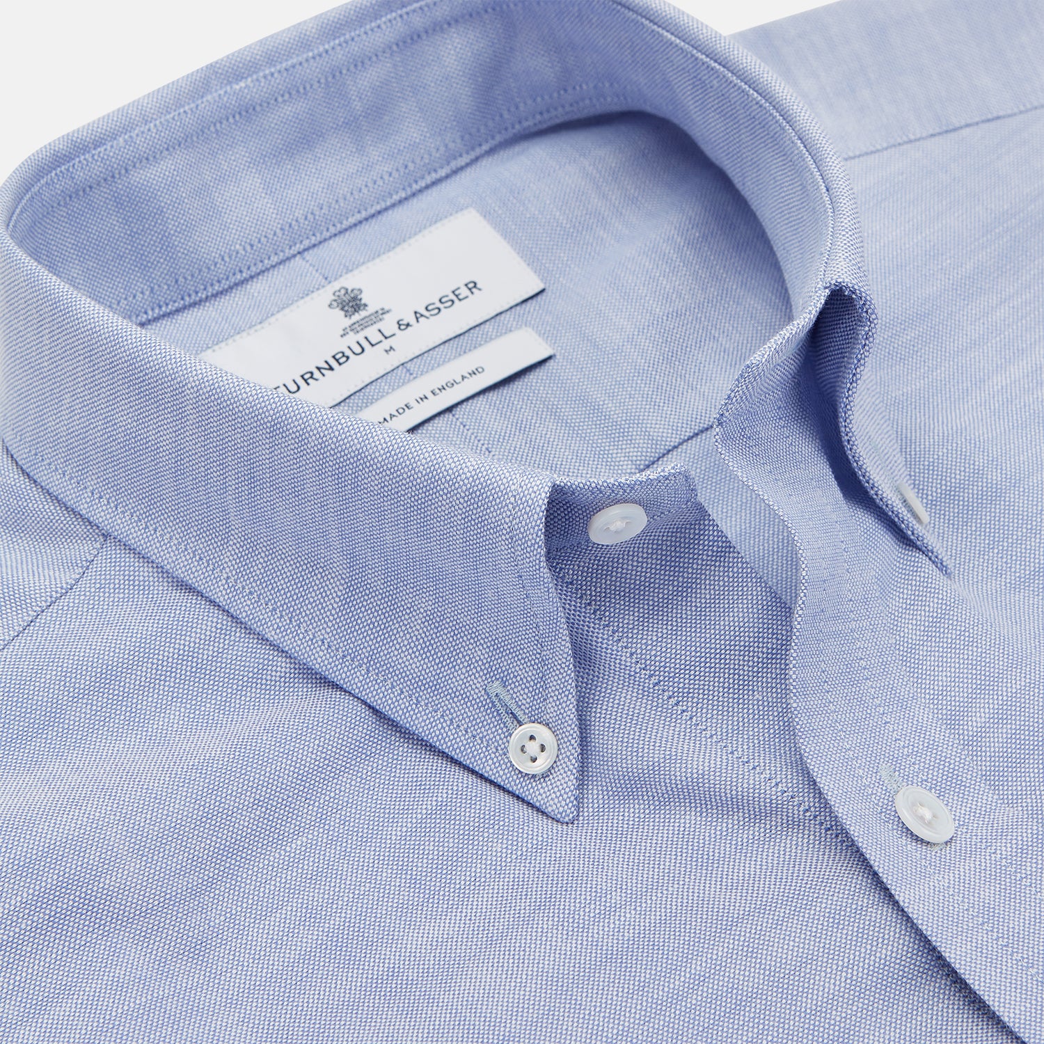 View 2 of product The Turnbull & Asser Mid-Blue Chambray Weekend Fit Shirt features a Dorset collar, white buttons, and 1-button cuffs. It is laid flat on a white background.