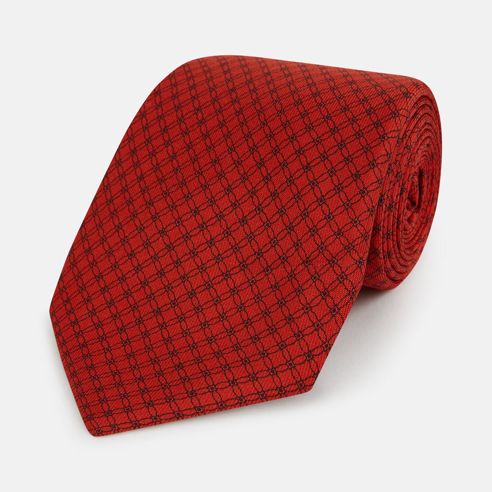 The Turnbull & Asser Red Lattice-Patterned Printed Silk Tie, crafted from fine English silk, is shown rolled up on a plain white background.