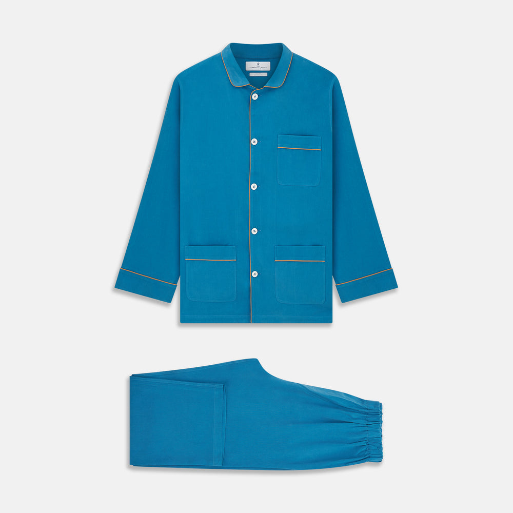 The Turnbull & Asser Blue Silk Hyde Pyjama Set features a modern fit with a long-sleeve button-up top, three pockets, white trim, and elastic-waist pants, all shown on a white background.