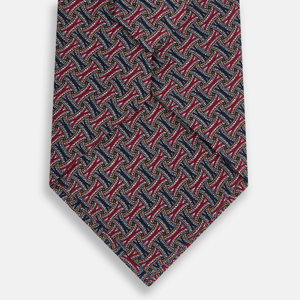 The Turnbull & Asser Burgundy and Navy Weave-Patterned Printed Silk Tie features an intricate geometric design, shown rolled on a plain white background.