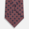 View 3 of product The Turnbull & Asser Antique Pink Medallion Silk Tie features a rolled-up design with small dark blue circular motifs on a white background.