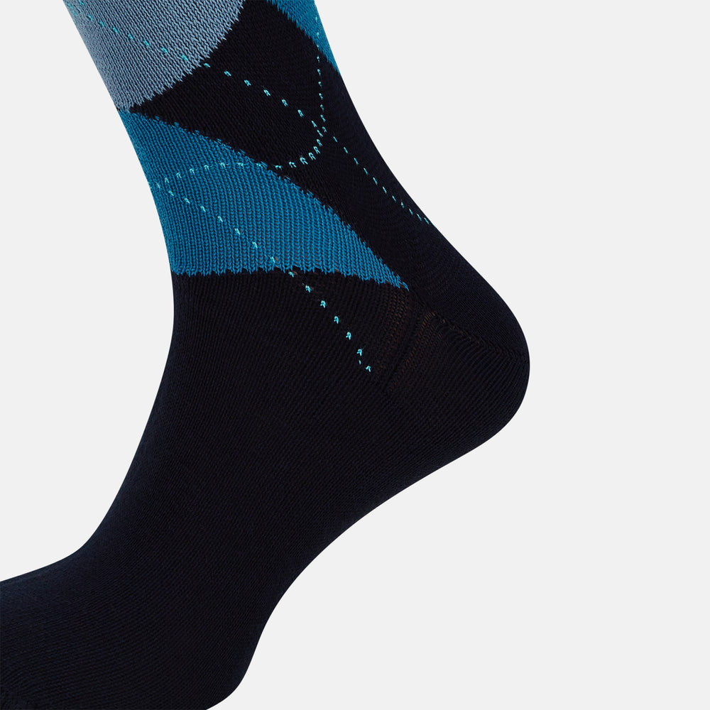 The Turnbull & Asser Navy Check Mid-Length Sock, crafted from ultra-soft cotton, features a blue and light blue argyle pattern with diamond shapes and dotted lines, and is showcased against a plain white background.