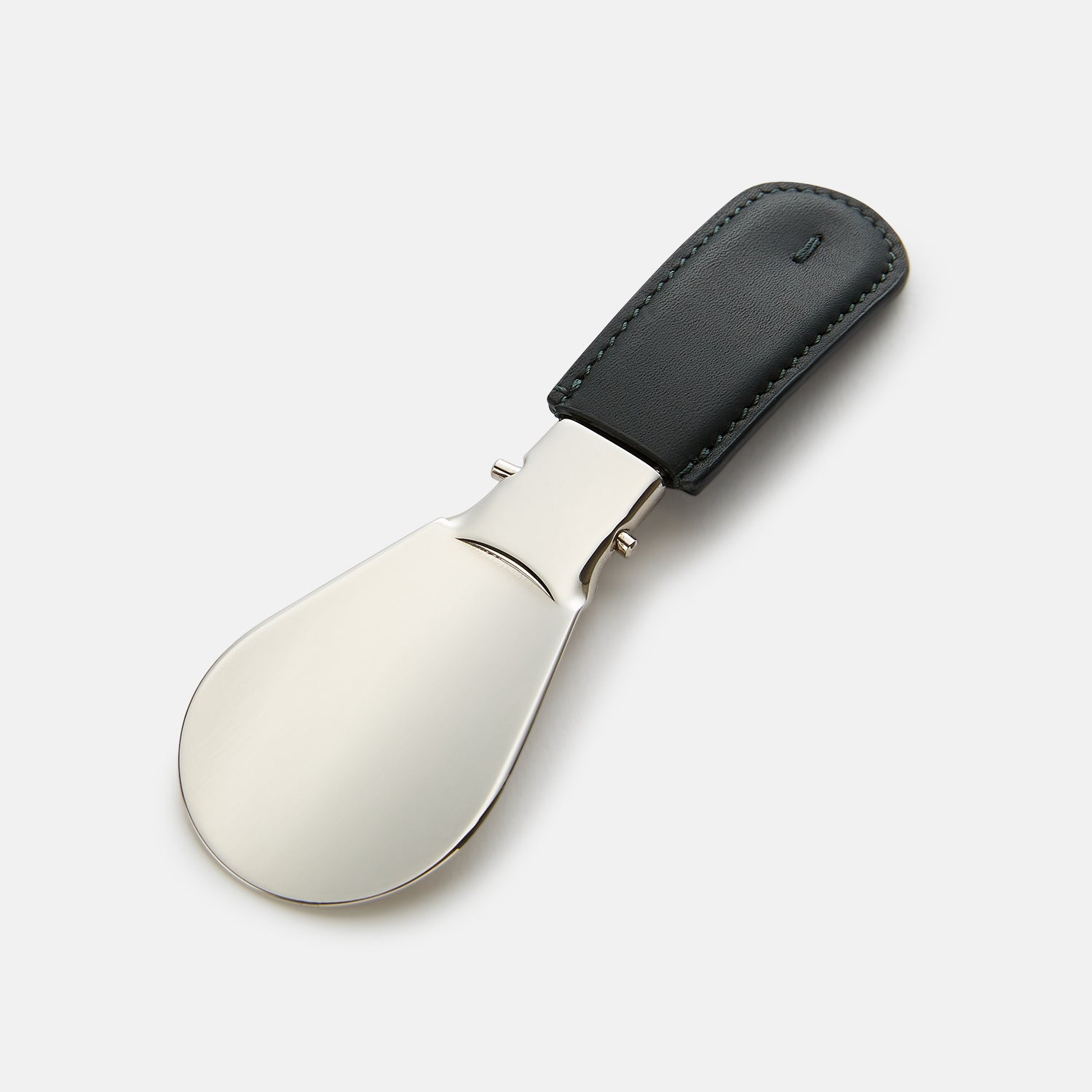 View 1 of product The Turnbull & Asser Forest Green Travel Shoe Horn features a wide, smooth metal blade and a forest green leather handle, shown against a plain white background.