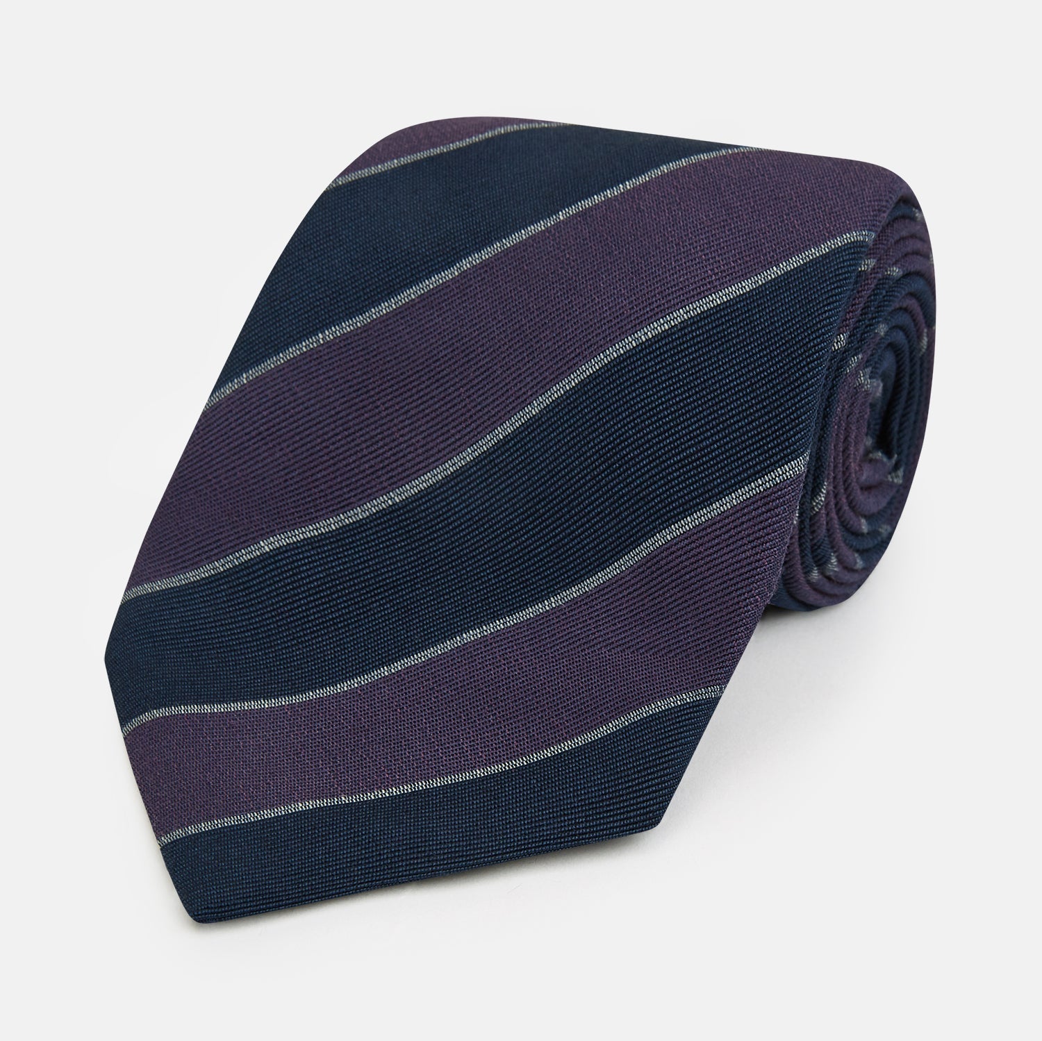 View 1 of product The Turnbull & Asser Purple And Navy Block Stripe Silk Blend Tie features dark navy and deep purple stripes with thin light gray lines, making it a refined formal accessory. Displayed on a white background.
