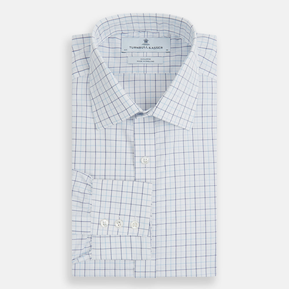 The Blue Overlay Grid Check Mayfair Shirt by Turnbull & Asser features a light blue and white grid check pattern with long sleeves and button-up design, making it a versatile wardrobe staple. Displayed on a plain white background.