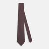 View 2 of product The Turnbull & Asser Burgundy Geometric Silk Tie, crafted in Britain, features a repeating pattern of light blue and white squares and diamonds. The neatly rolled tie is shown against a plain white background.