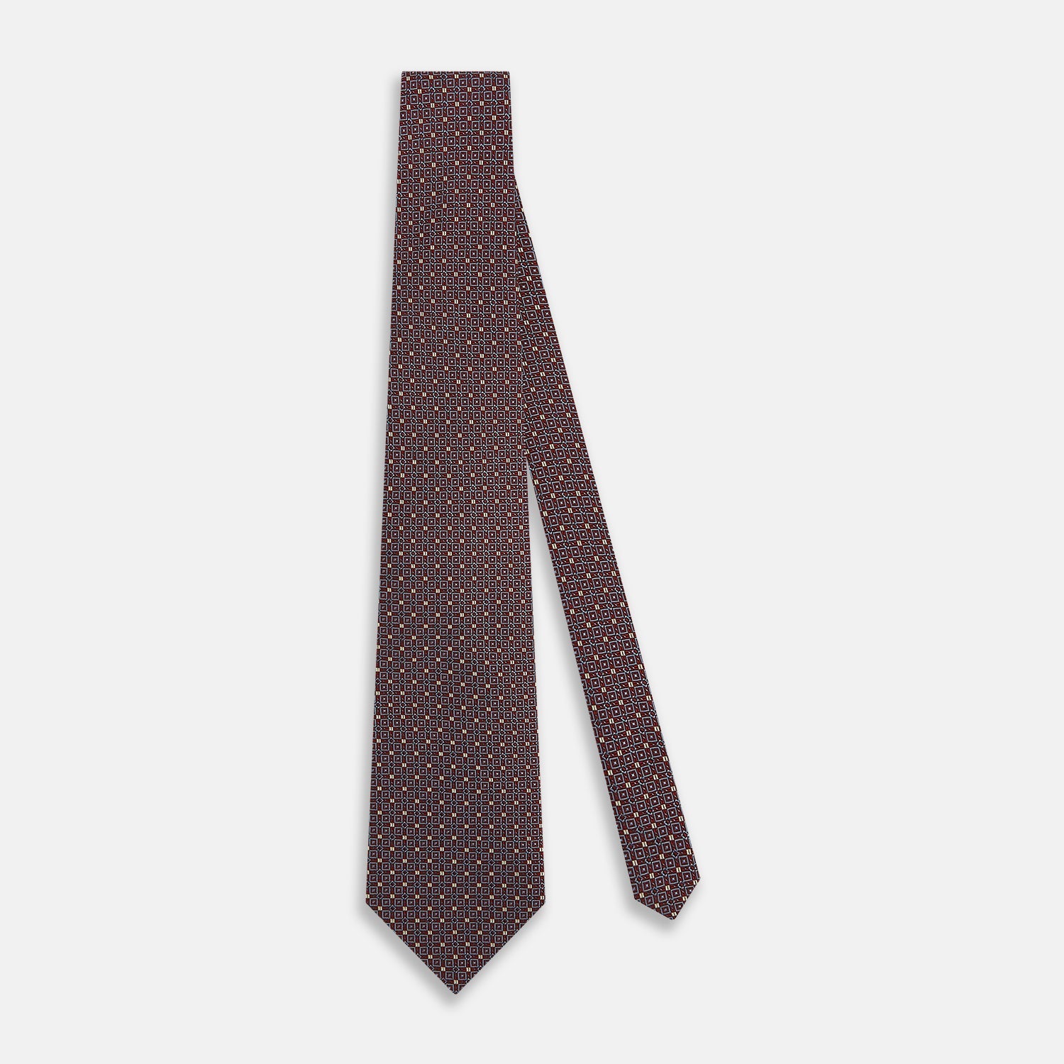 View 2 of product The Turnbull & Asser Burgundy Geometric Silk Tie, crafted in Britain, features a repeating pattern of light blue and white squares and diamonds. The neatly rolled tie is shown against a plain white background.