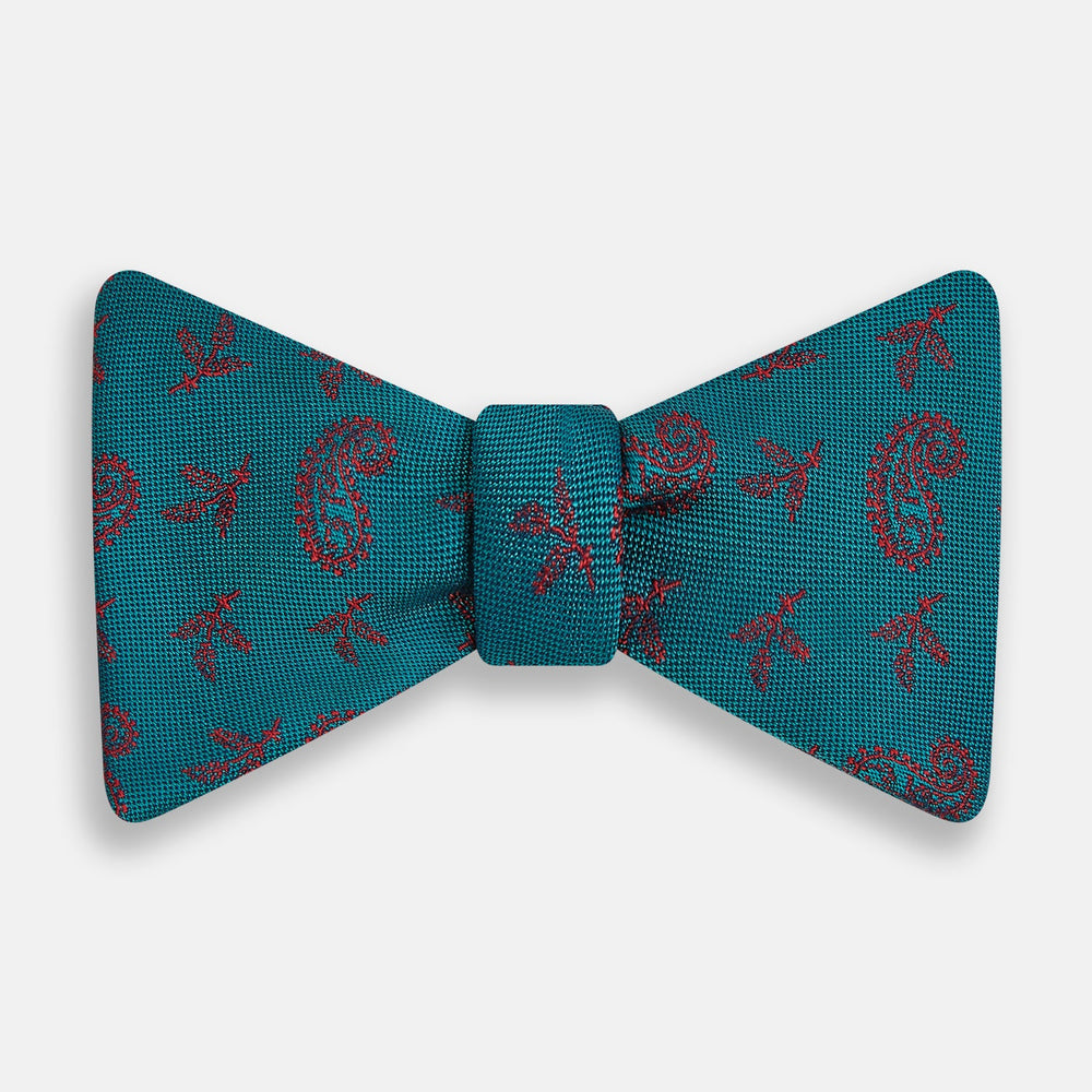 The Turnbull & Asser Teal Paisley Silk Bow Tie, featuring a red paisley and bee pattern, adds a touch of British elegance and formal refinement to your ensemble.