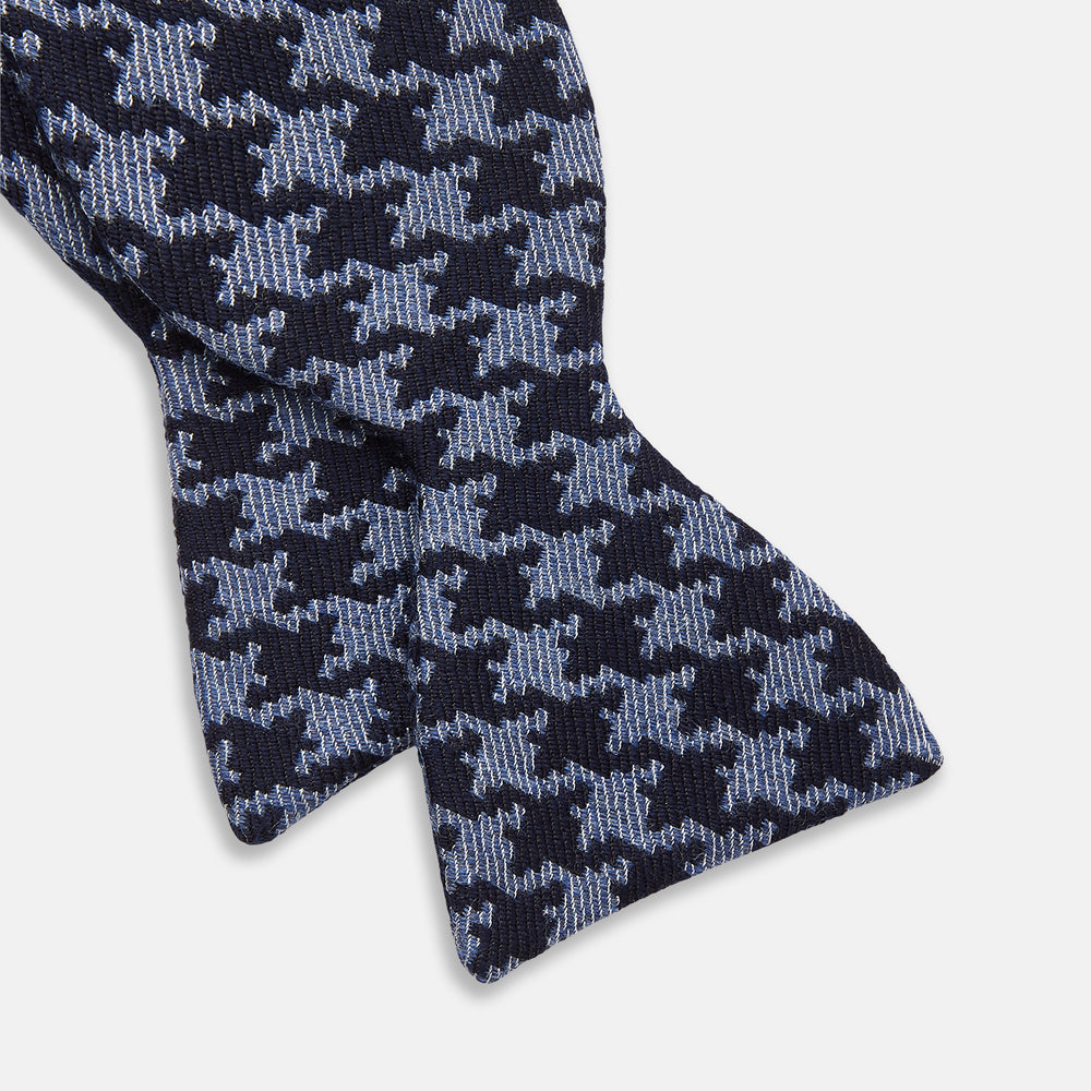 The Turnbull & Asser Navy and Blue Houndstooth Wool Blend Bow Tie features a self-tying design with a blue and black houndstooth pattern, showcased on a plain white background.