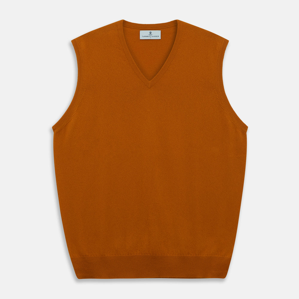 The Rust Ifor Slipover by Turnbull & Asser, a sleeveless V-neck in burnt orange, is made from lightweight Scottish cashmere and displayed flat on a white background.