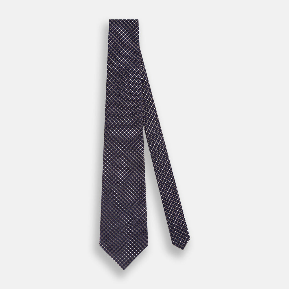 The Turnbull & Asser Silver and Navy Diamond Silk Tie features a neatly rolled silk design with a diagonal grid of small, light squares and lines, displayed on a plain background—perfect for an elegant, professional look.