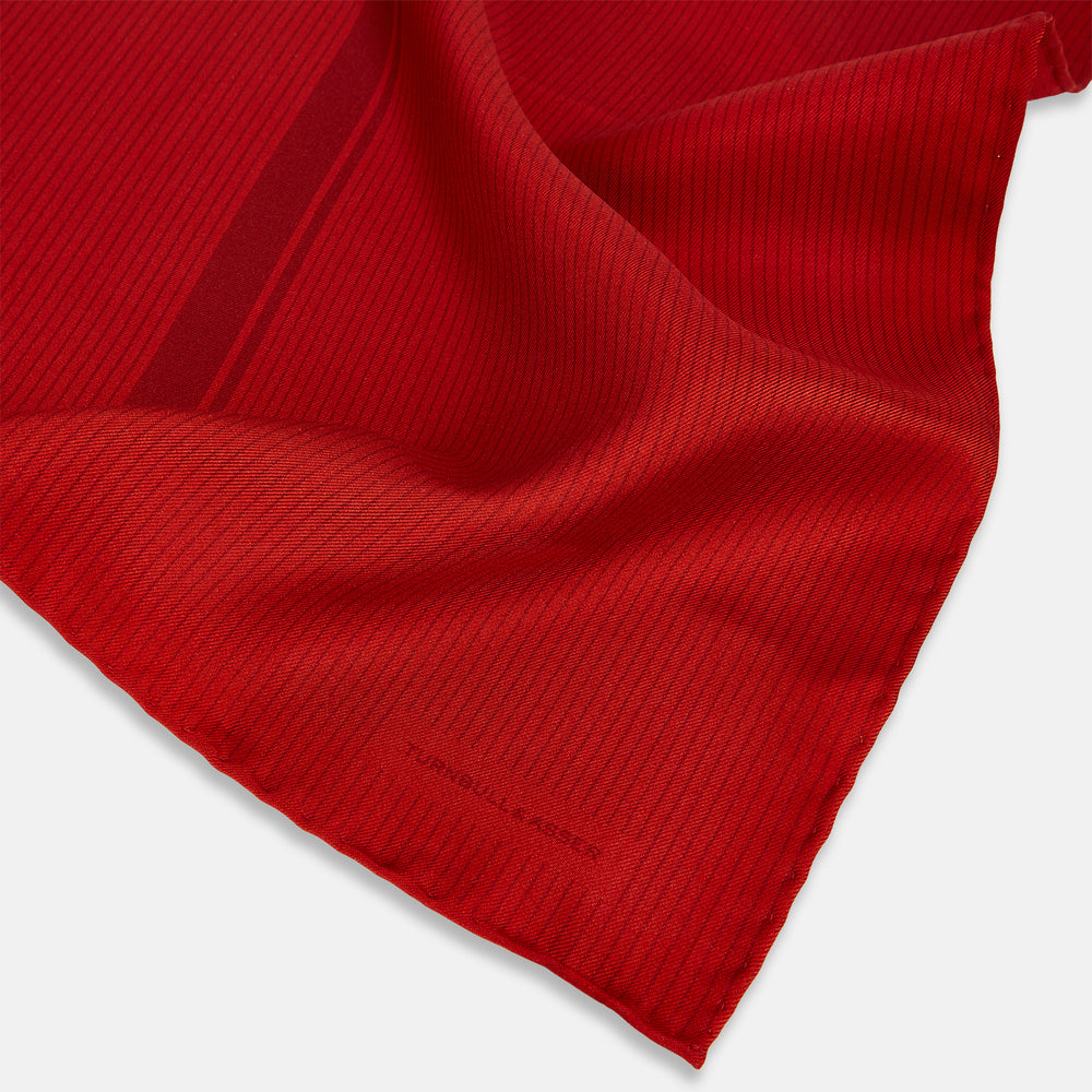 The Red and Burgundy Stripe Silk Pocket Square by Turnbull & Asser features subtle vertical stripes and a darker red stripe along one side, with “Turnbull & Asser” embossed in the fabric and a textured, turned-down corner.