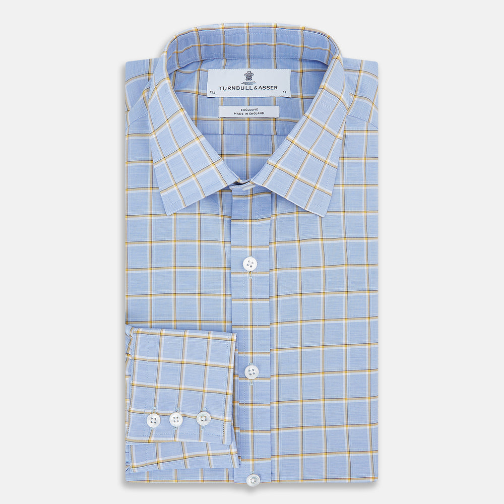 The Turnbull & Asser Blue and Yellow Windowpane Mayfair Shirt is crafted from fine Italian cotton, featuring a light blue base with yellow and white checks, shown on a plain white background.