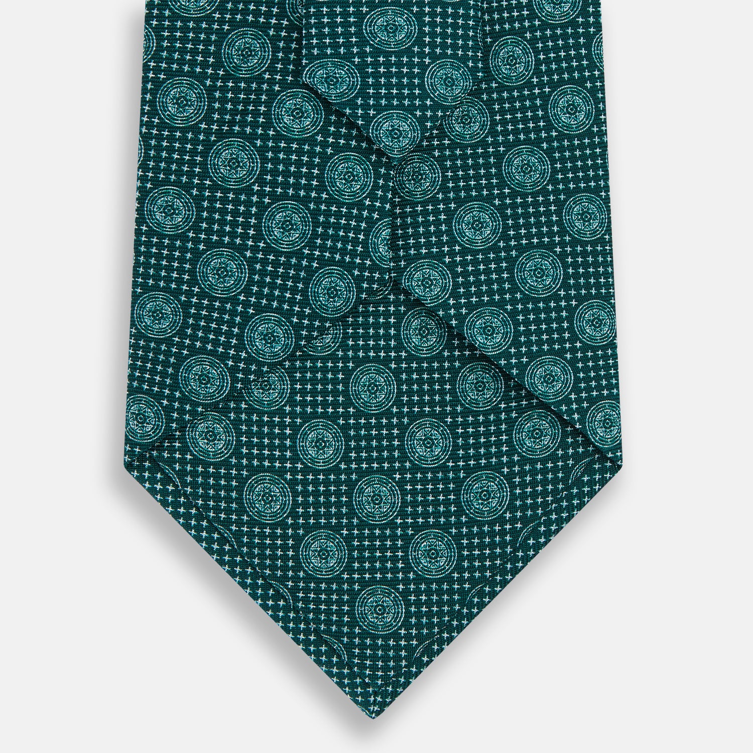 View 3 of product The Forest Green Medallion Printed Silk Tie by Turnbull & Asser features a repeating medallion pattern in lighter green tones, crafted from English silk and shown rolled up on a plain white background.